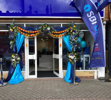 Entrance decorated with blue and yellow drapes and floral arrangements for a celebration.