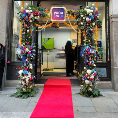 A shop entrance decorated with flowers and a red carpet for an event.