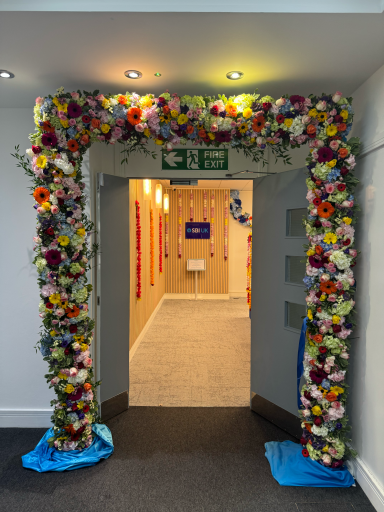 Floral archway leading to a hallway with decorative elements and signage.